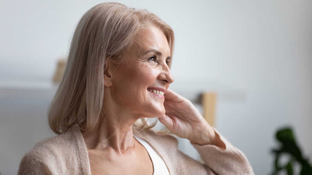 Older woman smiling and happy, not needing glasses after getting cataract surgery for clearer vision.